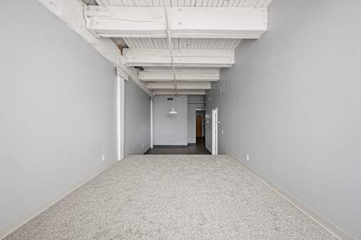 A long, empty hallway with a carpeted floor and white walls.