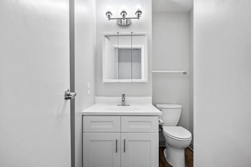 A white bathroom with a toilet, sink, and mirror.