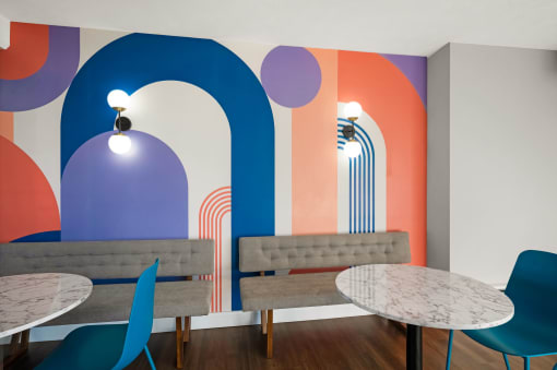a room with tables and chairs and a wall with a mural