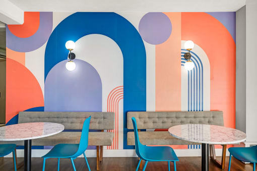 a restaurant with blue chairs and tables and a colorful wall with arches