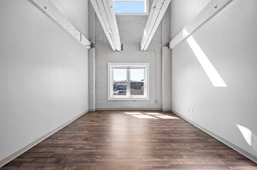 A room with wooden floors and a window overlooking a cityscape.