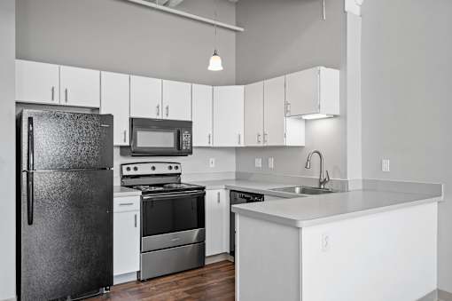 A modern kitchen with a black refrigerator, stove, and microwave.