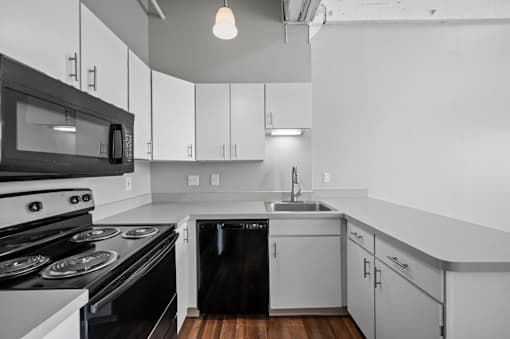 A black and white kitchen with a stove, oven, microwave, dishwasher, and sink.