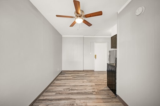 a living room with white walls and a ceiling fan