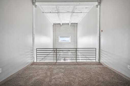 A white room with a carpeted floor and a metal gate.
