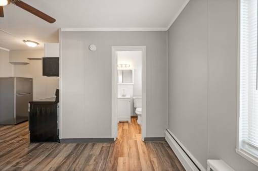 a living room with a hard wood floor and a door to a bathroom