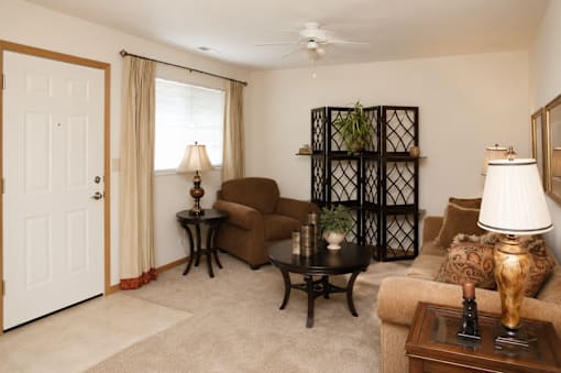 A living room with a brown couch, a black coffee table, and a white ceiling fan.