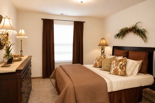 A bedroom with a large bed and a window with curtains.