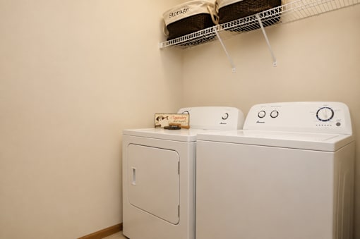Two white washing machines in a laundry room.