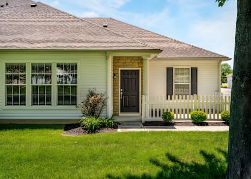 A house with a brown door and a white fence.