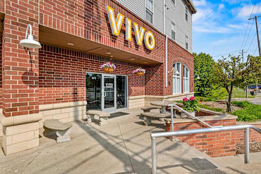 VIVO sign on a brick building with a bench in front. at Vivo Toledo Apartments, Toledo, 43607