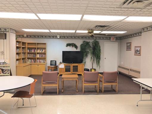 A room with a television, chairs, and a table.