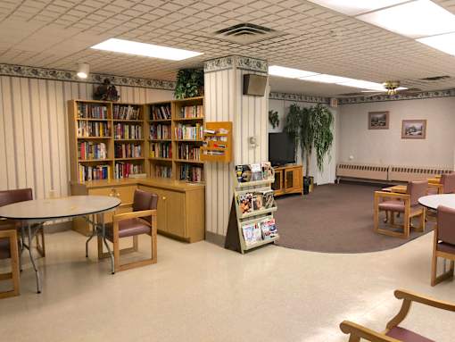 A library with tables, chairs, and bookshelves.
