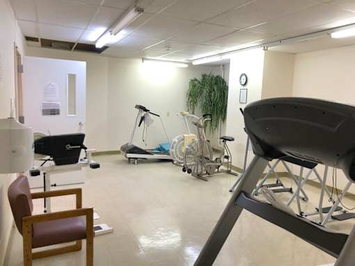 A room with a chair, a table, and a treadmill.