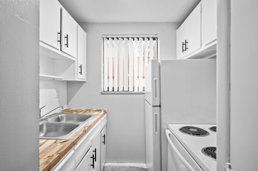 a white kitchen with a sink and a refrigerator