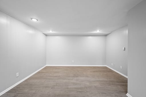 an empty room with a wood floor and white walls
