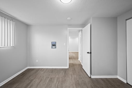 the living room and hallway of an empty house with white walls and wood floors