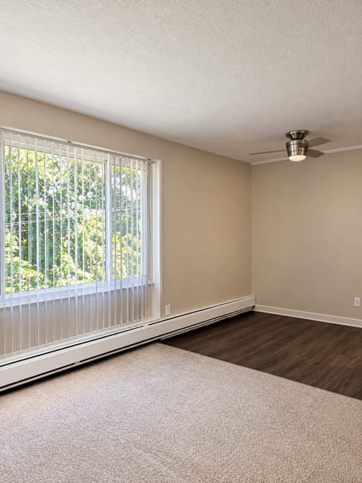 A room with a window covered by white blinds and a ceiling fan.