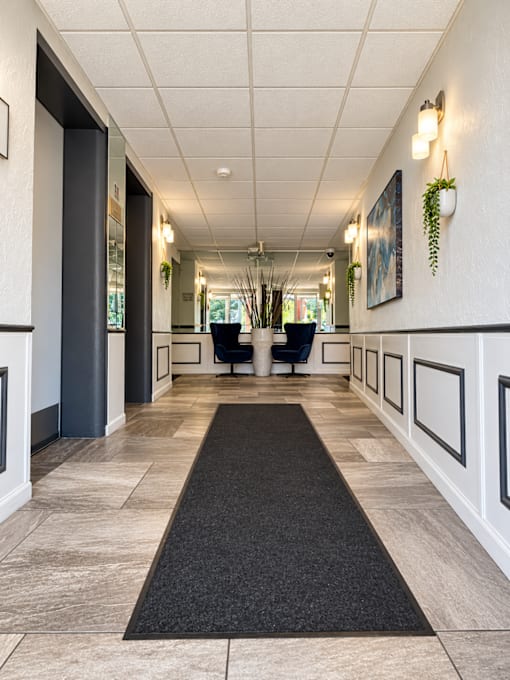 A hallway with a black carpet and white walls.