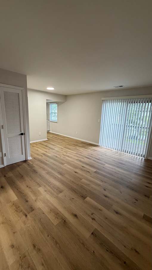 A room with wooden flooring and a window with blinds.