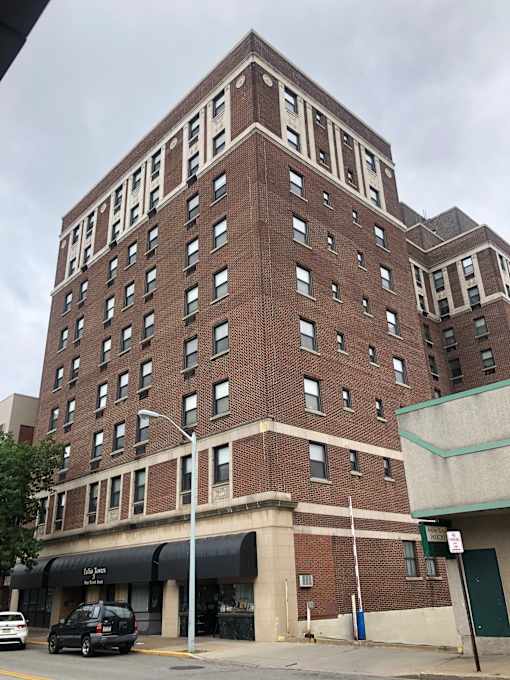 A tall brick building with a black car parked in front.