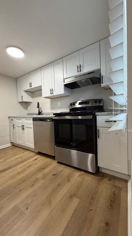 A kitchen with stainless steel appliances and white cabinets.
