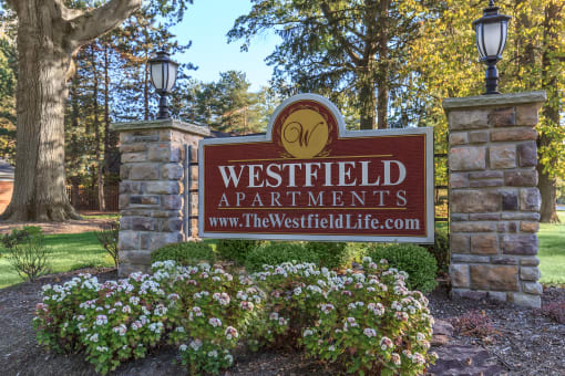 a sign for westfield apartments with flowers in front of it