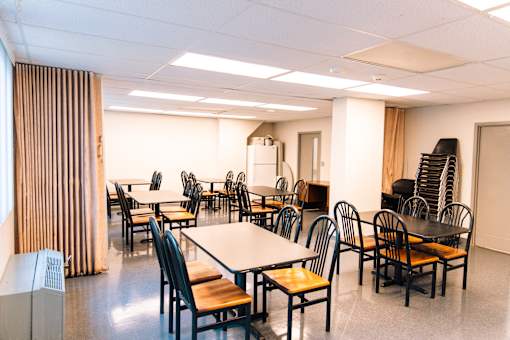 A room with tables and chairs and a whiteboard.