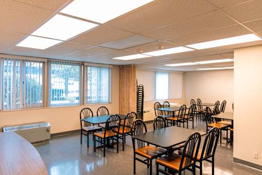 A room with tables and chairs and a window.