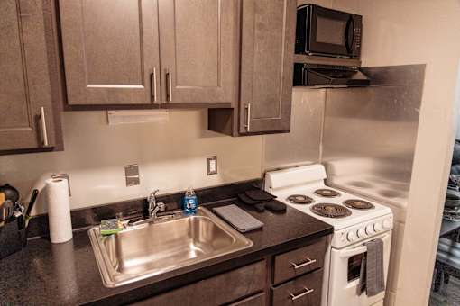 A kitchen with a white stove and a silver sink.