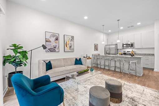 A blue armchair sits in a living room with a white couch and a rug. at The Lumos Apartments, Cleveland, Ohio