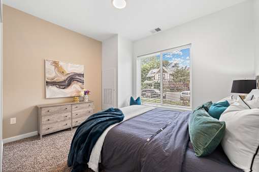 A bedroom with a large bed and a painting on the wall. at The Lumos Apartments, Ohio, 44106