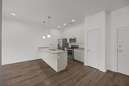 A kitchen with white cabinets and a wooden floor. at The Lumos Apartments, Cleveland, Ohio