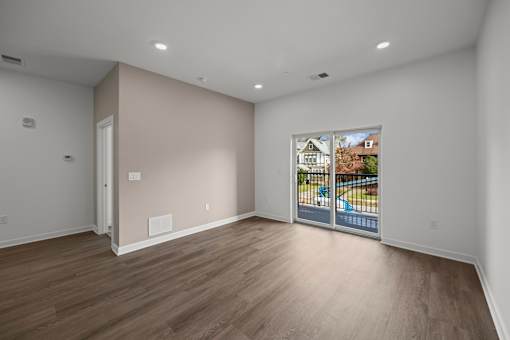 A room with a wooden floor and a picture of a house on the wall. at The Lumos Apartments, Cleveland 44106