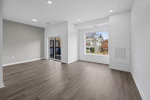 A room with wooden flooring and a large window showing a house. at The Lumos Apartments, Ohio, 44106