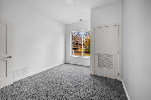 A room with a grey carpet and a white door. at The Lumos Apartments, Ohio