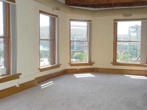 an empty room with three windows and a carpeted floor