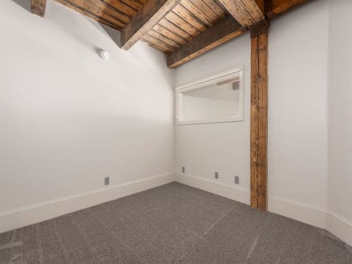 a bedroom with white walls and a ceiling with wooden beams
