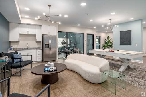 A modern kitchen with a breakfast bar and a living room area with a sofa and a coffee table. at Park Lamont Townhomes Apartments, Cleveland