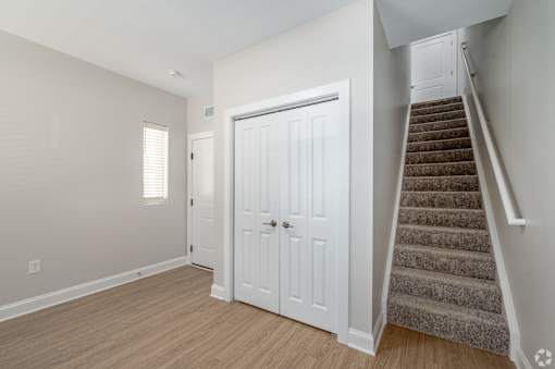 A white door is in a room with a staircase. at Park Lamont Townhomes Apartments, Cleveland 44106