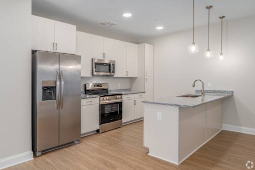 A modern kitchen with stainless steel appliances and wooden floors. at Park Lamont Townhomes Apartments, Cleveland, OH, 44106