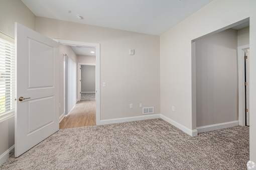 A room with a carpeted floor and a door on the left. at Park Lamont Townhomes Apartments, Cleveland