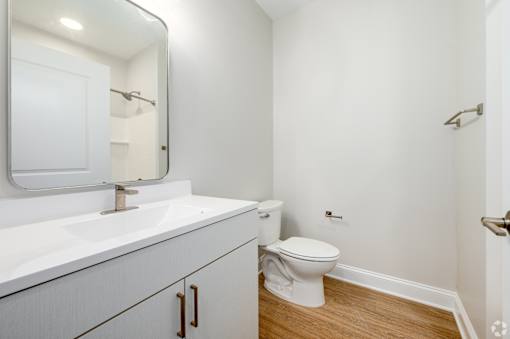 A white bathroom with a toilet and sink. at Park Lamont Townhomes Apartments, Cleveland