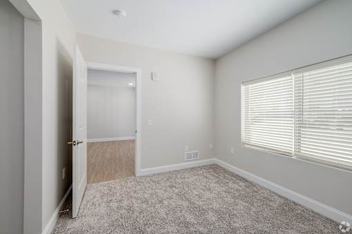 A room with a carpeted floor and a window with blinds. at Park Lamont Townhomes Apartments, Ohio