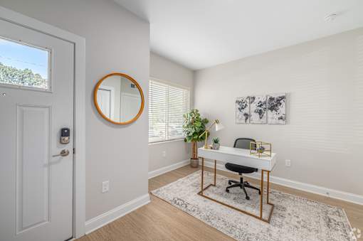 A white door with a round mirror on the wall next to a desk with a plant on it. at Park Lamont Townhomes Apartments, Cleveland