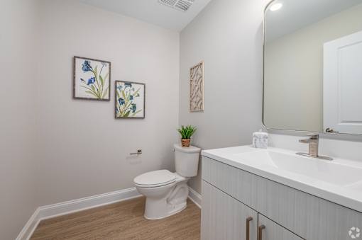 A white toilet sits next to a white sink in a small bathroom. at Park Lamont Townhomes Apartments, Cleveland, Ohio