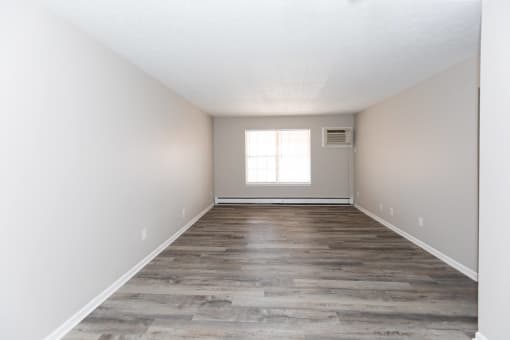 an empty room with wood floors and a window