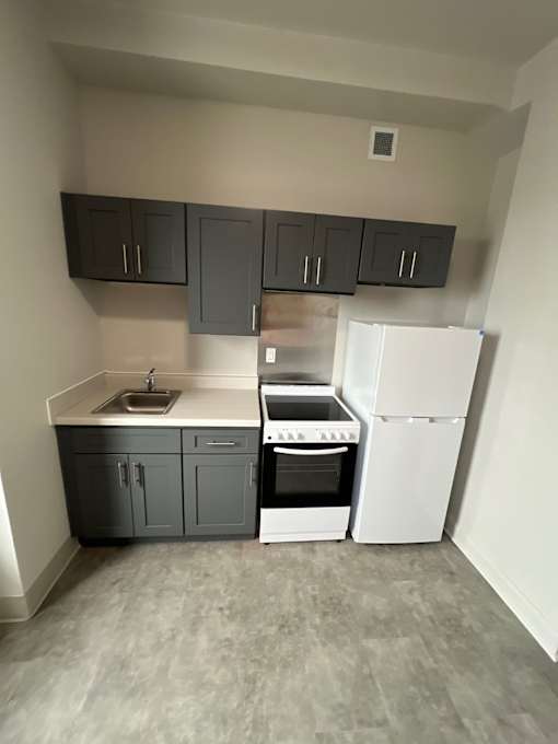 A kitchen with a white fridge and a sink.