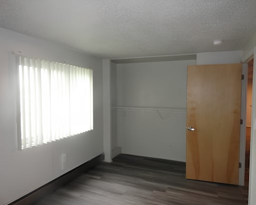 A room with a wooden door and a window with blinds.