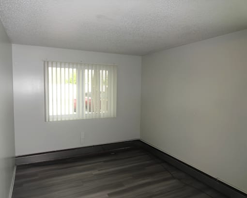 A room with a window and wooden floors.